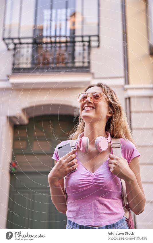 Fröhliche junge Frau, die ihren Urlaub auf einer Straße in der Stadt genießt Glück Teenager genießen Kopfhörer Feiertag reisen Spaß sorgenfrei Vergnügen heiter
