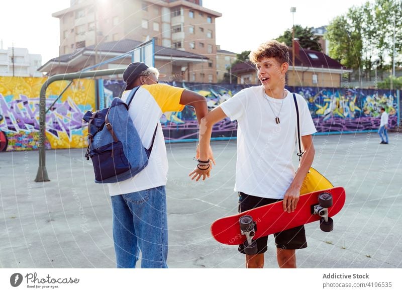 Zwei Teenager schütteln sich die Hände und lachen auf der Straße Herbst Rucksack schwarz Junge Kaukasier heiter Großstadt farbenfroh Gesellschaft Tageslicht