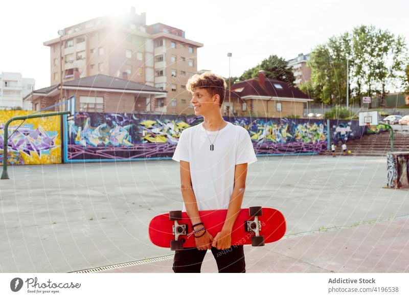 Hübscher kaukasischer Teenager mit Skateboard posiert auf der Straße Rücklicht Korb Junge Kaukasier Großstadt farbenfroh Gericht Spaß Graffiti gutaussehend