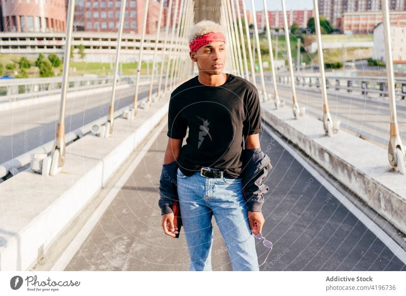 Hübscher schwarzer Junge auf der Straße attraktiv Brücke heiter Großstadt farbenfroh selbstbewusst Tageslicht ethnisch gutaussehend Kopftuch horizontal Jacke