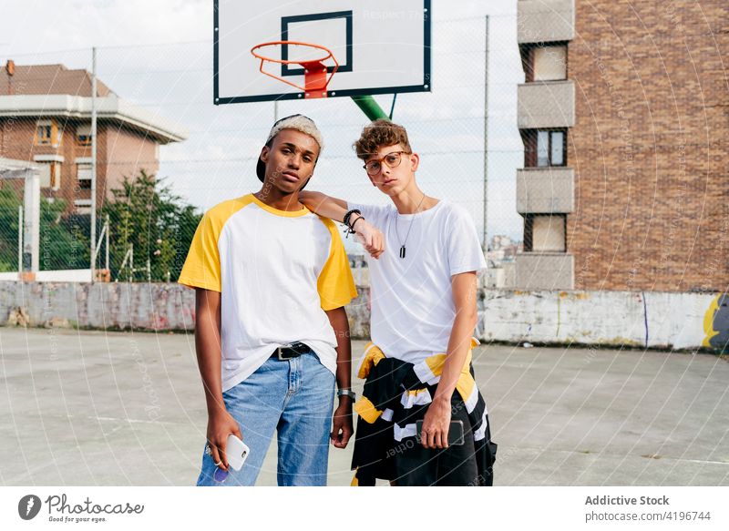 Zwei Teenager stehen auf dem städtischen Basketballplatz und schauen in die Kamera Herbst schwarz Junge Kaukasier Großstadt farbenfroh Gesellschaft Tageslicht