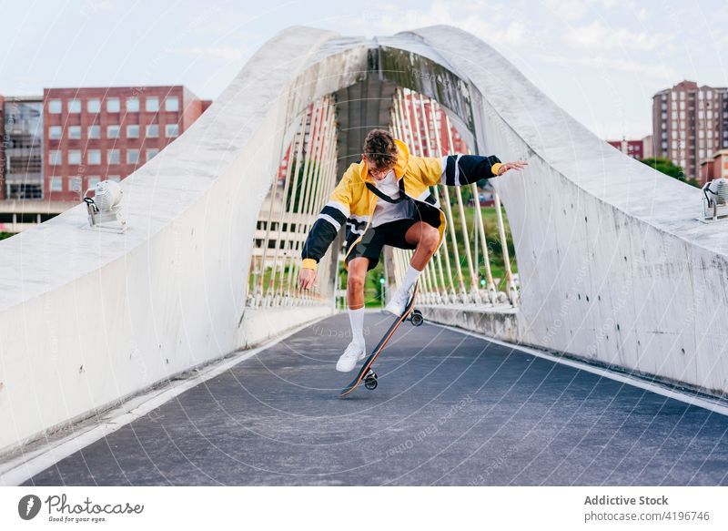 Kaukasischer Teenager springt mit Skateboard auf der Brücke in der Stadt Herbst blond Junge Kaukasier Großstadt farbenfroh selbstbewusst Tageslicht horizontal