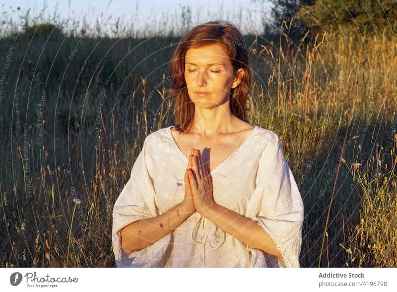 Ruhige Frau meditiert auf einem Feld im Sommer meditieren Natur Yoga üben ruhig Achtsamkeit Sprit Kleid Gebet gestikulieren Gelassenheit Harmonie friedlich
