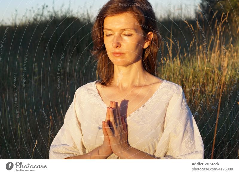 Ruhige Frau meditiert auf einem Feld im Sommer meditieren Natur Yoga üben ruhig Achtsamkeit Sprit Kleid Gebet gestikulieren Gelassenheit Harmonie friedlich