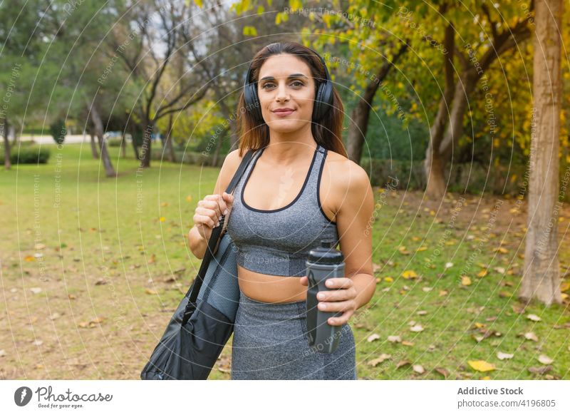 Frau in Sportkleidung und mit Yogamatte im Park Yogi Unterlage vorbereiten schlank Inhalt Wellness Gesundheit Vitalität heiter passen Sportbekleidung Harmonie
