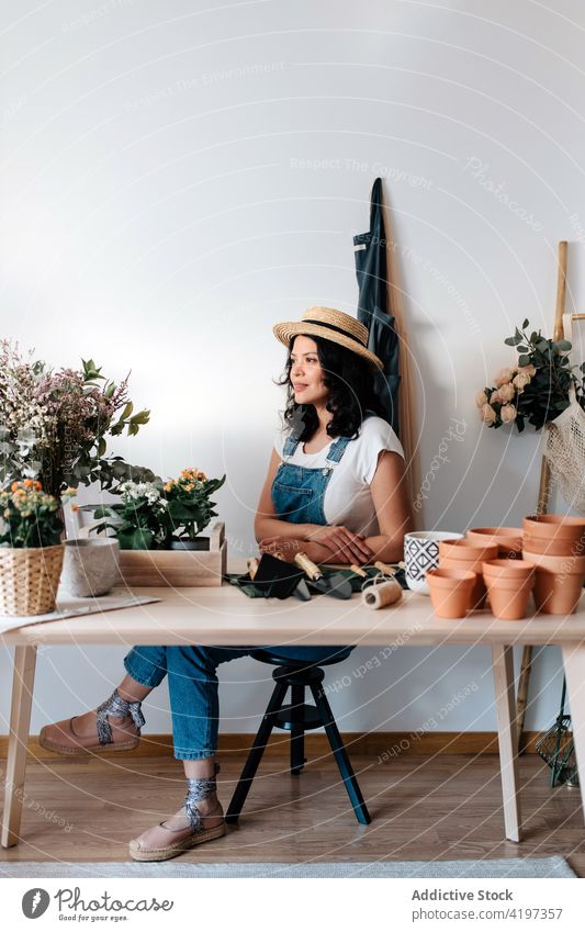 Gärtner sitzt am Tisch in einem Haus in der Nähe von Pflanzen und Blumen geschnitten Laubwerk Botanik vegetieren natürlich Frau sortiert Werkzeug Kelle Reihe