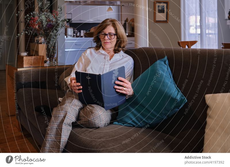 Konzentrierte ältere Frau mit Tablet auf der Couch Senior Liege Tablette lesen Browsen e-Buch Wohnzimmer Hobby Brille Sofa Apparatur Gerät Internet online