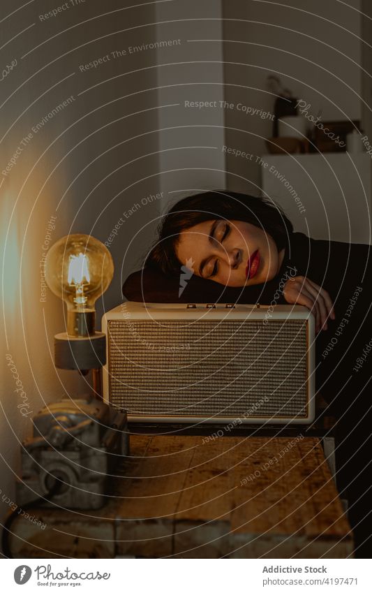Ruhige Frau mit geschlossenen Augen und Glühbirne im Vintage-Raum verträumt altehrwürdig retro Licht Wachtraum Gelassenheit leuchten Radio Kulisse fettarm