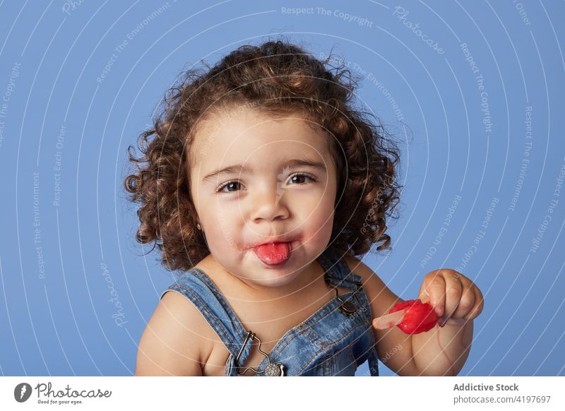 Niedliches kleines Mädchen leckt Eiscreme Kind lustig Stieleis lutschen Speiseeis Zunge zeigen geschmackvoll Leckerbissen Kindheit positiv Jeansstoff