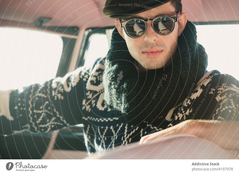 Modischer Mann mit Sonnenbrille und Strickjacke in einem Fahrzeug Model Stil retro Ornament Strickwaren Porträt weich Pullover 50s hell altehrwürdig stylisch