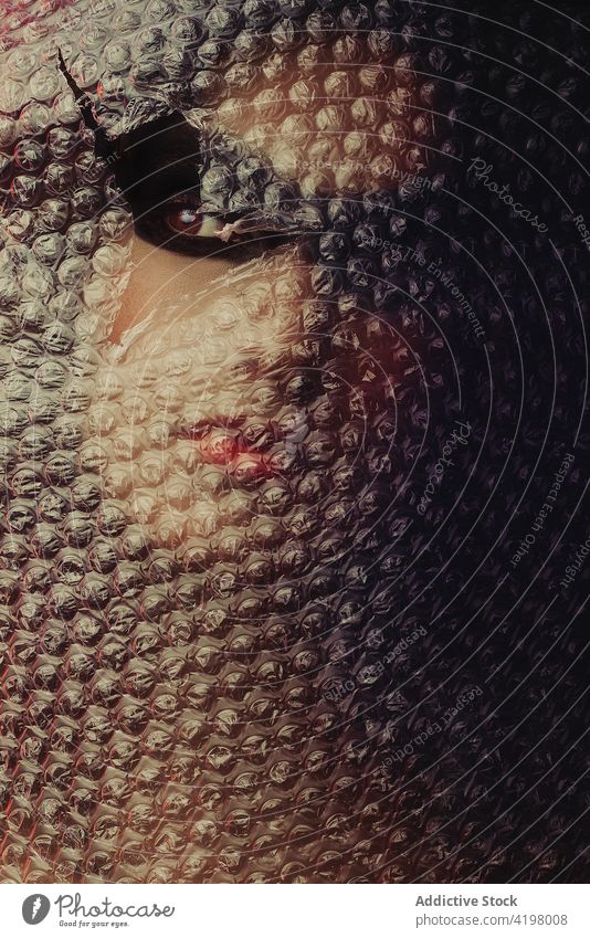 Frau schaut durch Loch in Luftpolsterfolie Model Schaumblase umhüllen Stil Mysterium Rätsel dunkel Atelier feminin Vorschein kreativ elegant rote Lippen ruhig