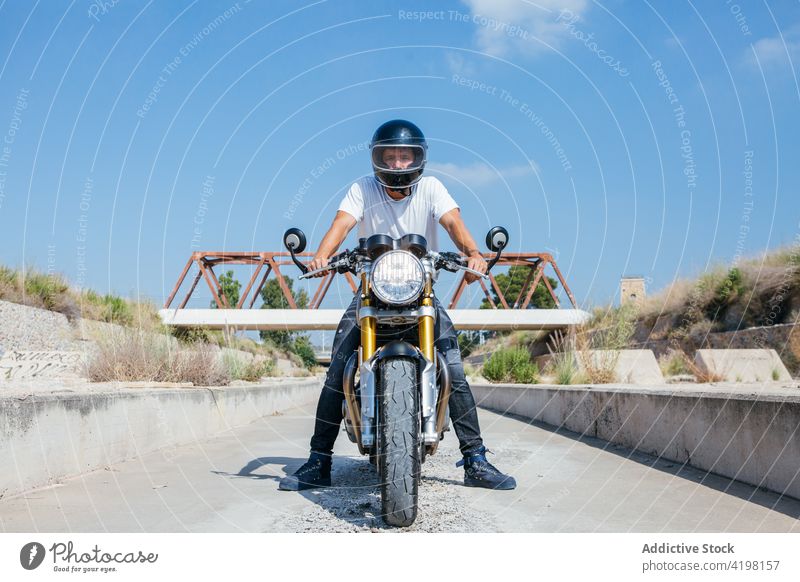 Männlicher Motorradfahrer auf modernem Motorrad in einem Vorort Biker Mann Schutzhelm behüten cool Reiter selbstbewusst männlich Stil Fahrzeug sitzen brutal