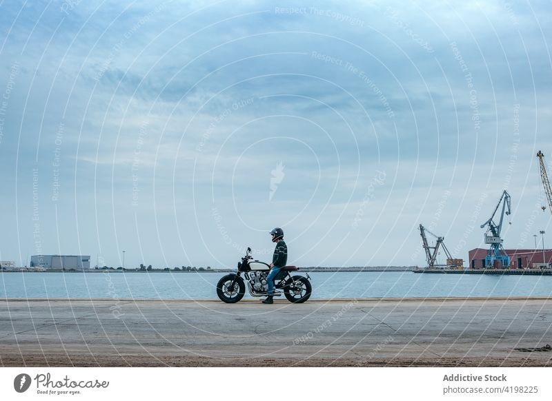 Anonymer Mann sitzt auf einem Motorrad und bewundert das Meer Stauanlage MEER sich[Akk] entspannen Stil cool Konstruktion Biker Erholung bewundern Seeküste