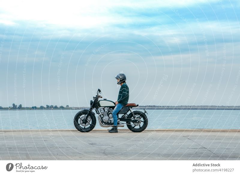 Anonymer Mann sitzt auf einem Motorrad und bewundert das Meer Stauanlage MEER sich[Akk] entspannen Stil cool Konstruktion Biker Erholung bewundern Seeküste