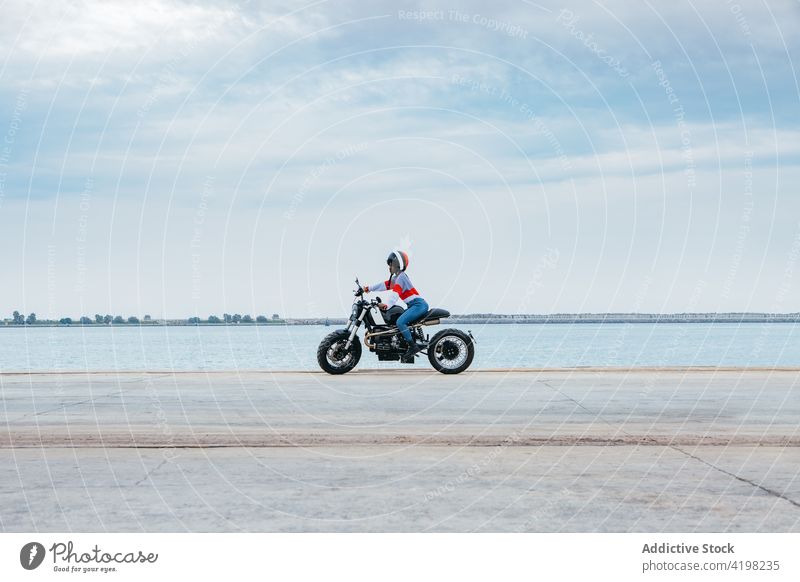 Anonyme trendige Dame fährt Motorrad in der Nähe des Meeres Frau Mitfahrgelegenheit Straße MEER Stil allein Biker Ausflug genießen reisen Fahrzeug jung trendy