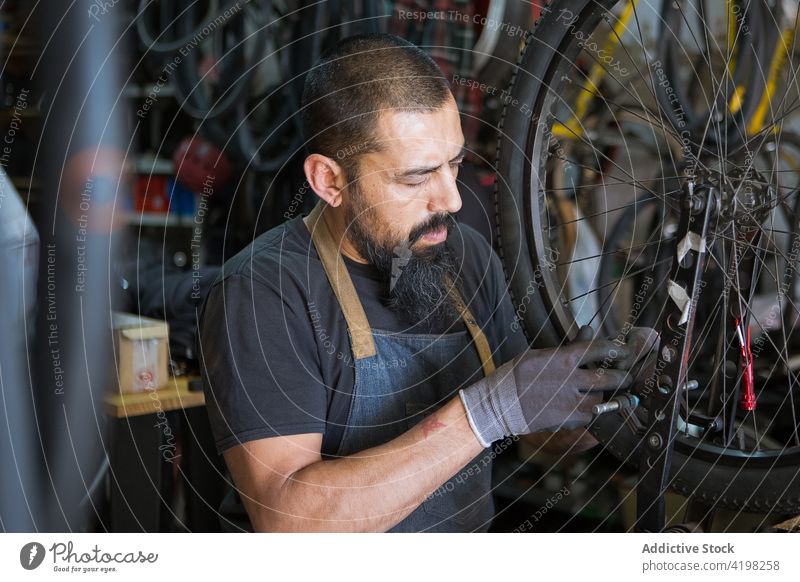 Bärtiger Mechaniker bei der Reparatur eines Fahrrads Mann Rad Garage Reifen Werkstatt Dienst Meister Fähigkeit männlich Fahrzeug vorbereiten professionell