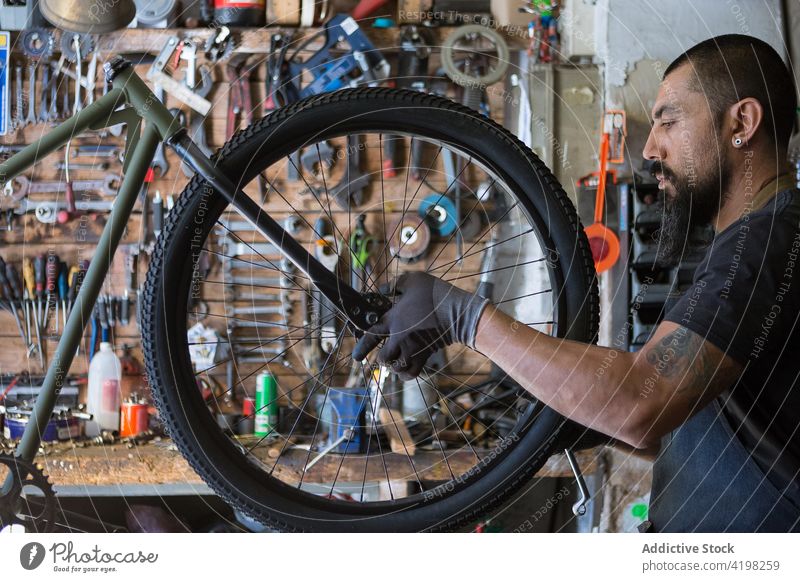 Bärtiger Mechaniker bei der Reparatur eines Fahrrads Mann Rad Garage Reifen Werkstatt Dienst Meister Fähigkeit männlich Fahrzeug vorbereiten professionell