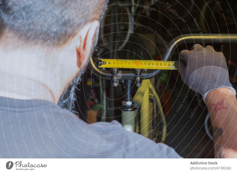 Gesichtsloser Mann misst Metalllenker mit Lineal Reparatur Garage messen Lenker Fahrrad Mechaniker fixieren Dienst männlich Fahrzeug Meister vorbereiten