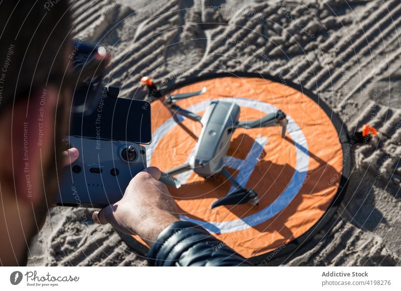 Anonymer Mann steuert Drohne in der Natur Dröhnen abgelegen Kontrolle arbeiten unbemannt Unterlage Landen Regler männlich Strand Gerät Apparatur benutzend Hobby