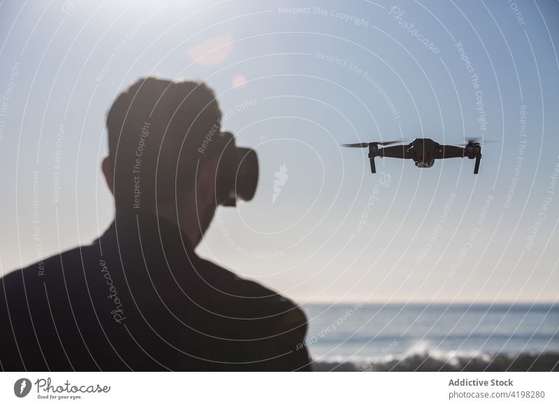 Anonymer Mann mit VR-Brille steuert Drohne am Meer arbeiten Dröhnen virtuell Realität Flug abgelegen Kontrolle männlich Fliege unbemannt Regler Gerät Apparatur