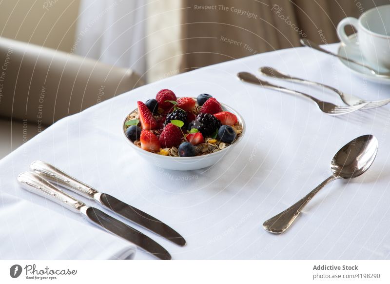 Leckeres Frühstück mit Müslischale und Beeren auf dem Tisch im Cafe Kaffee Silberwaren Schalen & Schüsseln Supernahrung Gesundheit Mahlzeit Erdbeeren Blaubeeren