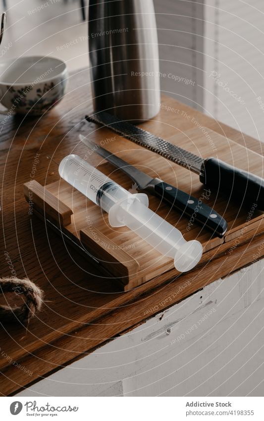 Messer mit kulinarischen Spritze auf Holztisch in der Küche platziert Schneidebrett Küchengeräte Thermoskanne Schalen & Schüsseln Werkzeug Utensil hölzern