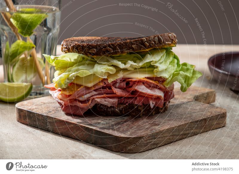 Gesundes Sandwich mit Blattsalat und Speck Belegtes Brot Salat knirschen Zuprosten appetitlich Holzplatte hölzern Ernährung Restaurant lecker kulinarisch