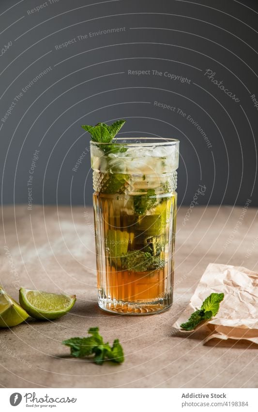 Glas kalter Cocktail mit Limette und Minzblättern Mojito Minze geschnitten Kalk cool aktualisieren Rum Alkohol Eis Holzplatte geschmackvoll Zitrusfrüchte
