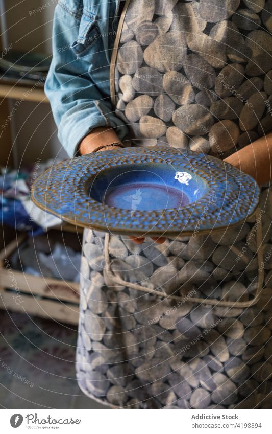 Gesichtsloser Töpfer zeigt eine Tonplatte in einem traditionellen Atelier Person manifestieren Teller Keramik Tonwaren Kunstgewerbler handgefertigt Handwerk