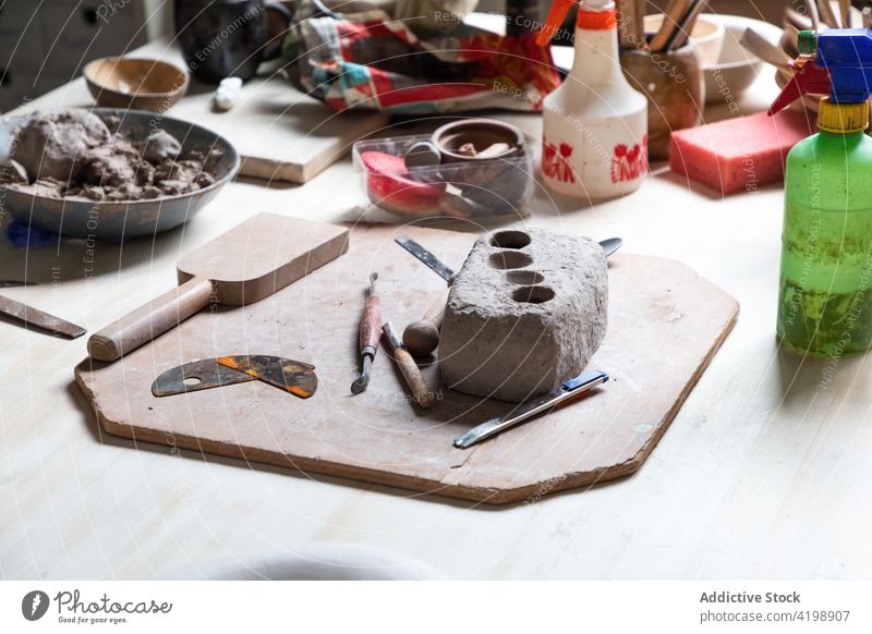 Tonstück mit verschiedenen Töpferwerkzeugen auf dem Tisch in der Werkstatt Töpferwaren Werkzeug Tonwaren Geschirr kreieren Basteln Kunst Handwerkskunst Leiste