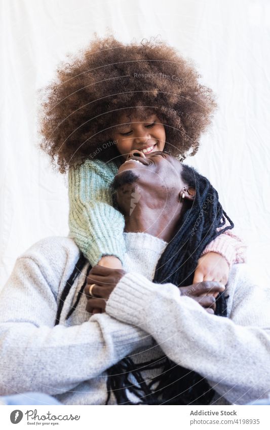 Liebevolle Tochter umarmt sanft den fröhlichen Vater Umarmen heiter Bonden schließen froh Streicheln Mädchen Papa Mann Rastalocken Kind Afro-Look genießen