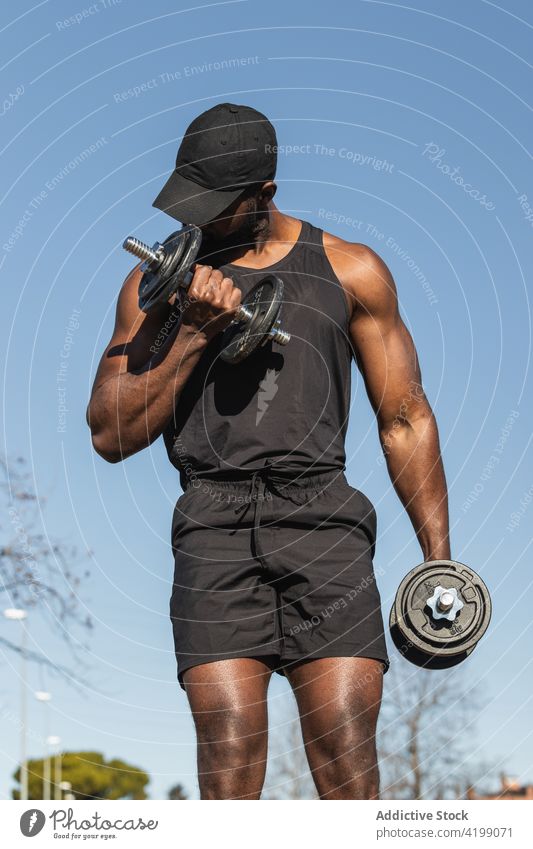 Unbekannter schwarzer Sportler mit Hanteln beim Training in der Stadt Athlet Kurzhantel Fitness muskulös Mann Körper Gewicht Gerät Sportbekleidung maskulin