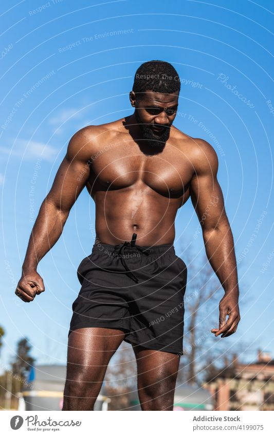 Starker ethnischer Sportler ruht sich beim Training auf dem Sportplatz aus nackter Torso stark ruhen muskulös Wellness Mann ohne Hemd Unterleib Hipster