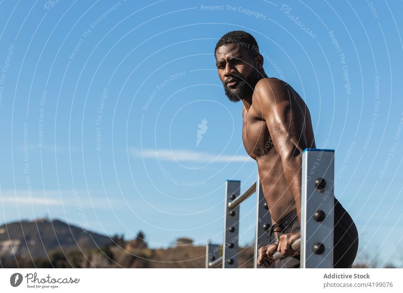 Starker schwarzer Sportler beim Training an der Bar in der Stadt hochziehen Übung muskulös stark Mann Muskel Fitness Sportbekleidung Afroamerikaner Kraft