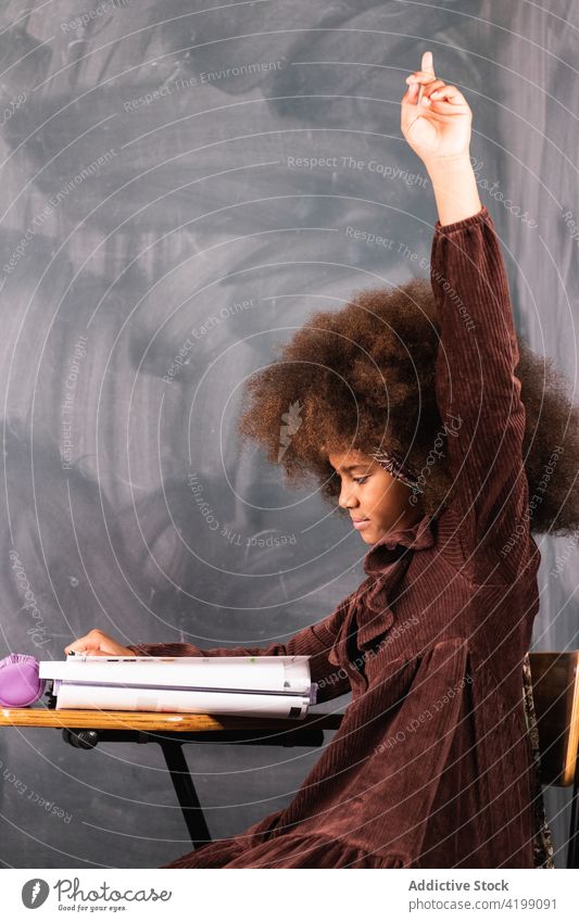 Schwarzes Mädchen mit erhobener Hand im Klassenzimmer während des Unterrichts Pupille Hand erhoben Lektion Schule Arm angehoben Schulmädchen lernen clever