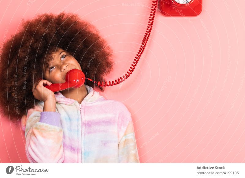 Schwarzes Mädchen spricht in einem Studio am Telefon sprechen altmodisch reden Kind retro rot Atelier ethnisch schwarz Afroamerikaner Afro-Look Frisur Anruf