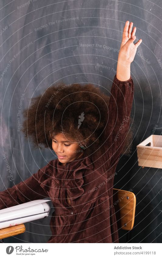 Schwarzes Mädchen mit erhobener Hand im Klassenzimmer während des Unterrichts Pupille Hand erhoben Lektion Schule Arm angehoben Schulmädchen lernen clever