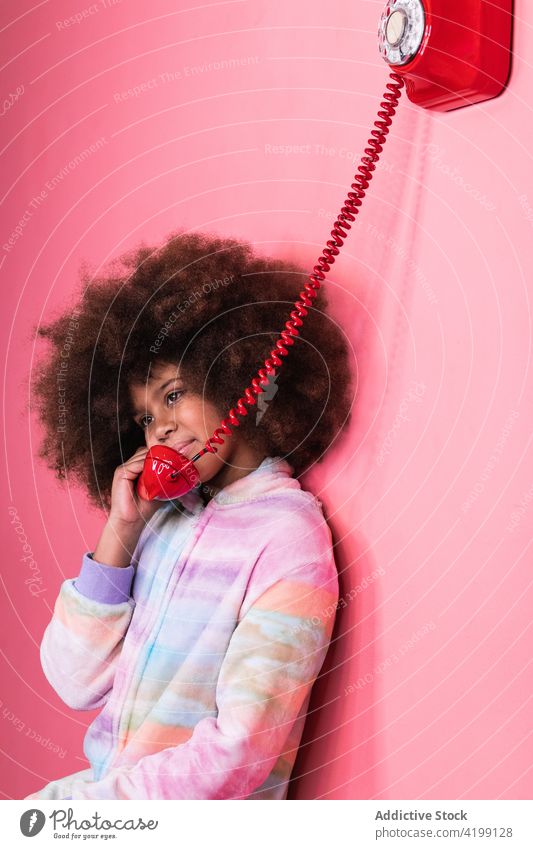 Schwarzes Mädchen spricht in einem Studio am Telefon sprechen altmodisch reden Kind retro rot Atelier ethnisch schwarz Afroamerikaner Afro-Look Frisur Anruf