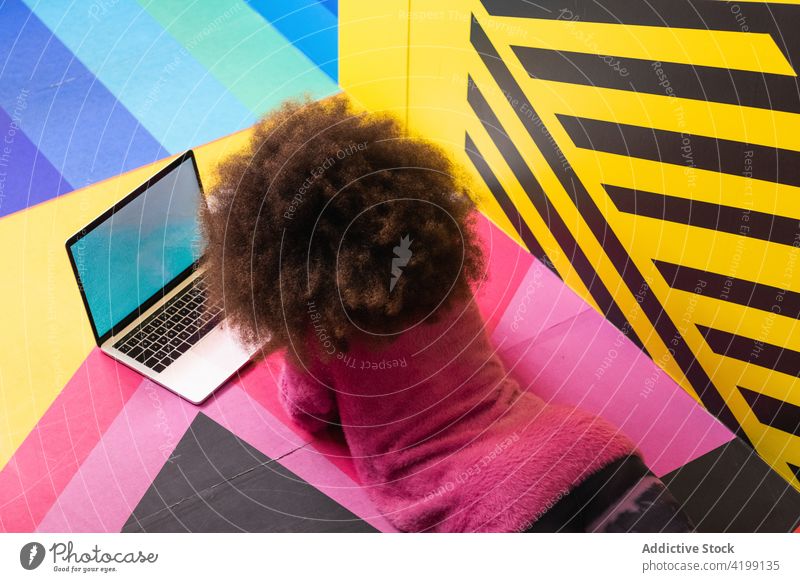 Anonymes schwarzes Mädchen benutzt Laptop im Studio Browsen Teenager farbenfroh Atelier lebhaft benutzend Internet soziale Netzwerke ethnisch Afroamerikaner