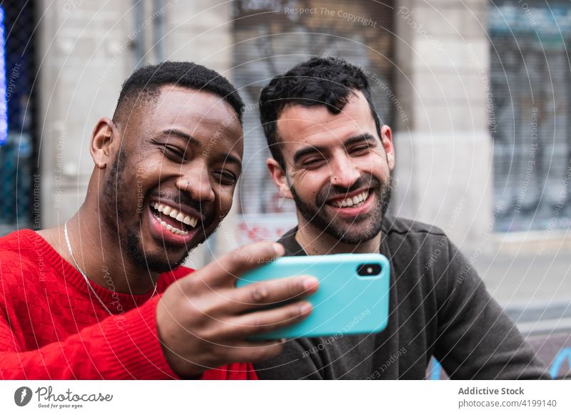 Fröhliche diverse Freunde, die auf einer Bank in der Stadt ein Selfie mit ihrem Smartphone machen Glück Moment Gedächtnis Straße Männer benutzend Apparatur