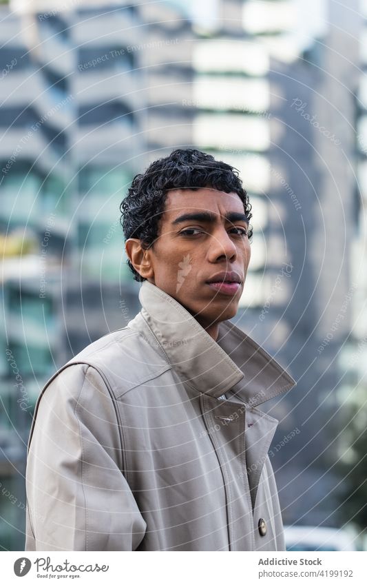 Stilvoller ethnischer Mann, der sich in einem Gebäude auf der Straße spiegelt Mode trendy Individualität Zeitgenosse Reflexion & Spiegelung Stadt Glasgebäude