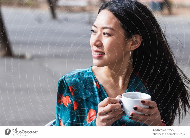 Langhaarige brünette asiatische Frau trinkt einen Kaffee auf der Terrasse eines Cafés Menschen Werkstatt Chinesisch Kaffeehaus Tasse Person trinken heiß