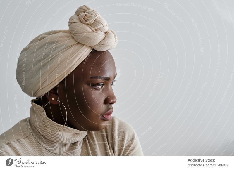 Selbstbewusste junge schwarze Frau mit Turban schaut weg Stil selbstbewusst traumhaft Model Porträt Vorschein Persönlichkeit feminin selbstsicher schick