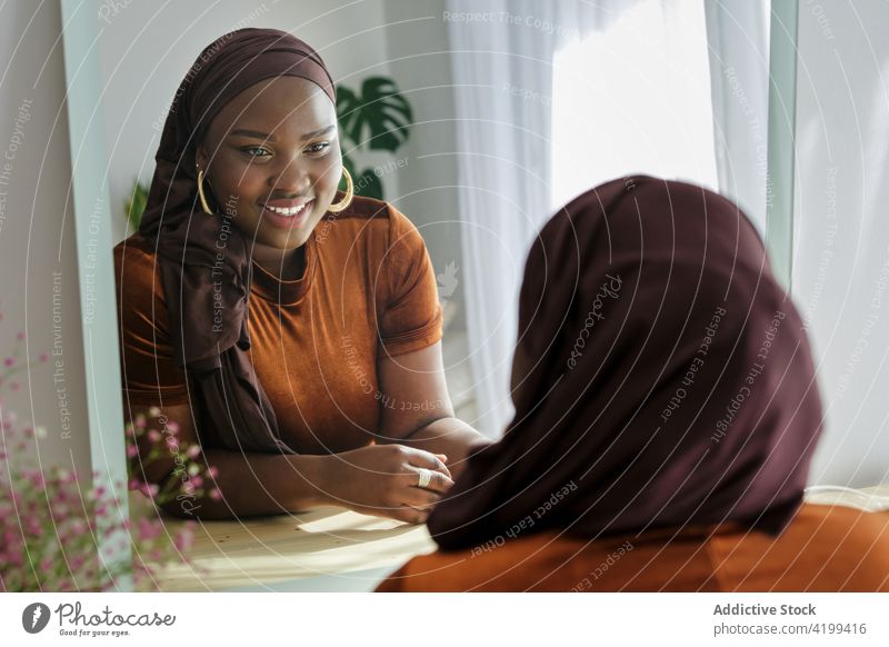 Glückliche junge ethnische Frau schaut in den Spiegel in einem modernen Raum Stil Reflexion & Spiegelung elegant Vorschein Mode Persönlichkeit trendy Windstille