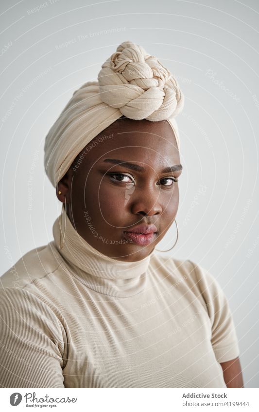 Selbstbewusste junge schwarze Frau mit Turban schaut in die Kamera Stil selbstbewusst traumhaft Model Porträt Vorschein Persönlichkeit feminin selbstsicher
