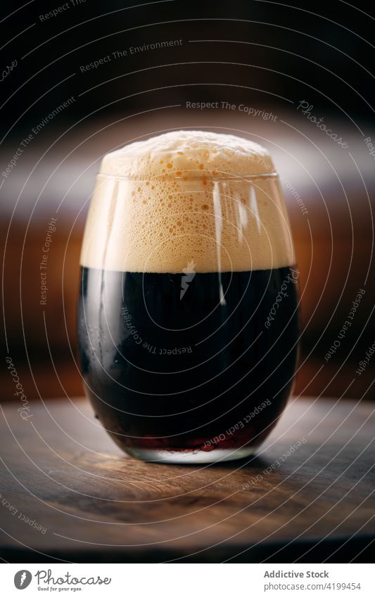 Ein Glas dunkles Bier auf dem Tisch dunkel Handwerk Gepäckträger brauen Bar trinken Alkohol schäumen geschmackvoll dienen lecker Pub Bierschaum kalt Brauerei