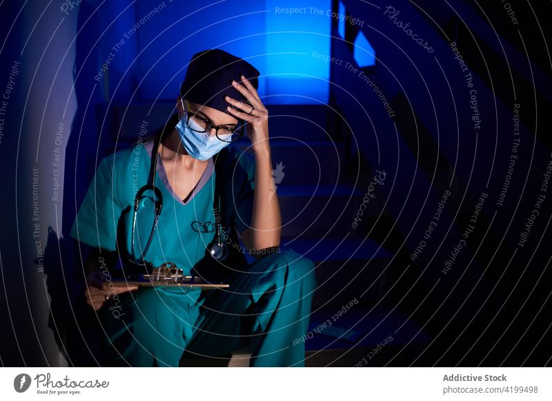 Nachdenklicher Arzt liest Dokumente im Dunkeln lesen Schriftstück nachdenklich Frau untersuchen medizinisch Bericht Sanitäter besinnlich Klinik dunkel Treppe