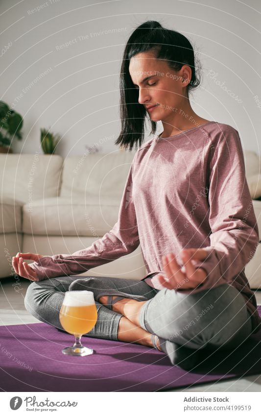 Frau beim Yoga mit einem Glas Bier zu Hause Lotus-Pose meditieren brauen padmasana Gelassenheit Mudra Unterlage sich[Akk] entspannen Wellness Gerät Windstille