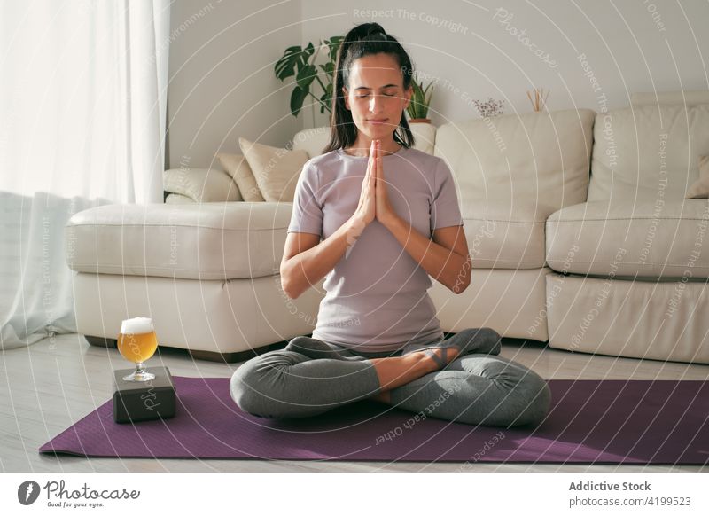 Frau beim Yoga mit einem Glas Bier zu Hause Lotus-Pose meditieren brauen padmasana Gelassenheit Mudra Unterlage sich[Akk] entspannen Wellness Gerät Windstille