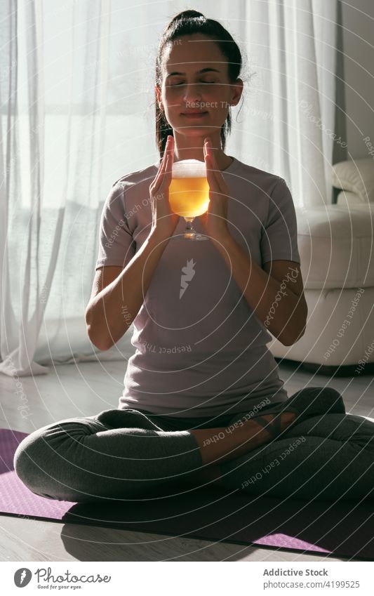 Frau in Lotus-Pose mit einem Glas Bier Yoga trinken Alkohol padmasana üben Asana heimwärts Unterlage Wohlbefinden Augen geschlossen Getränk sitzen Vitalität
